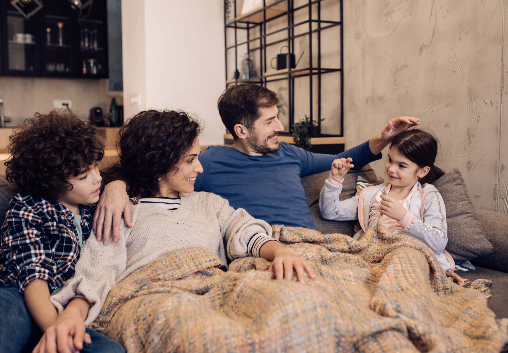 Family of four relaxing together on a cozy couch in a modern living room